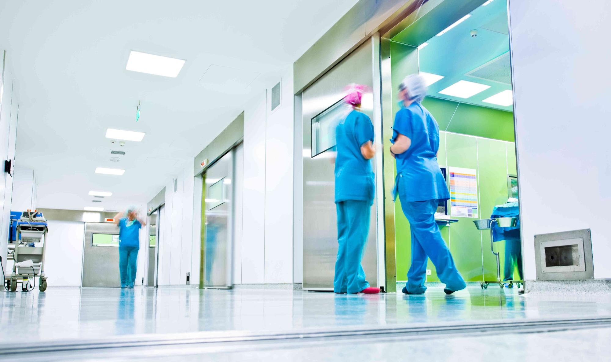 blurred figures wearing medical uniforms in hospital surgery cor